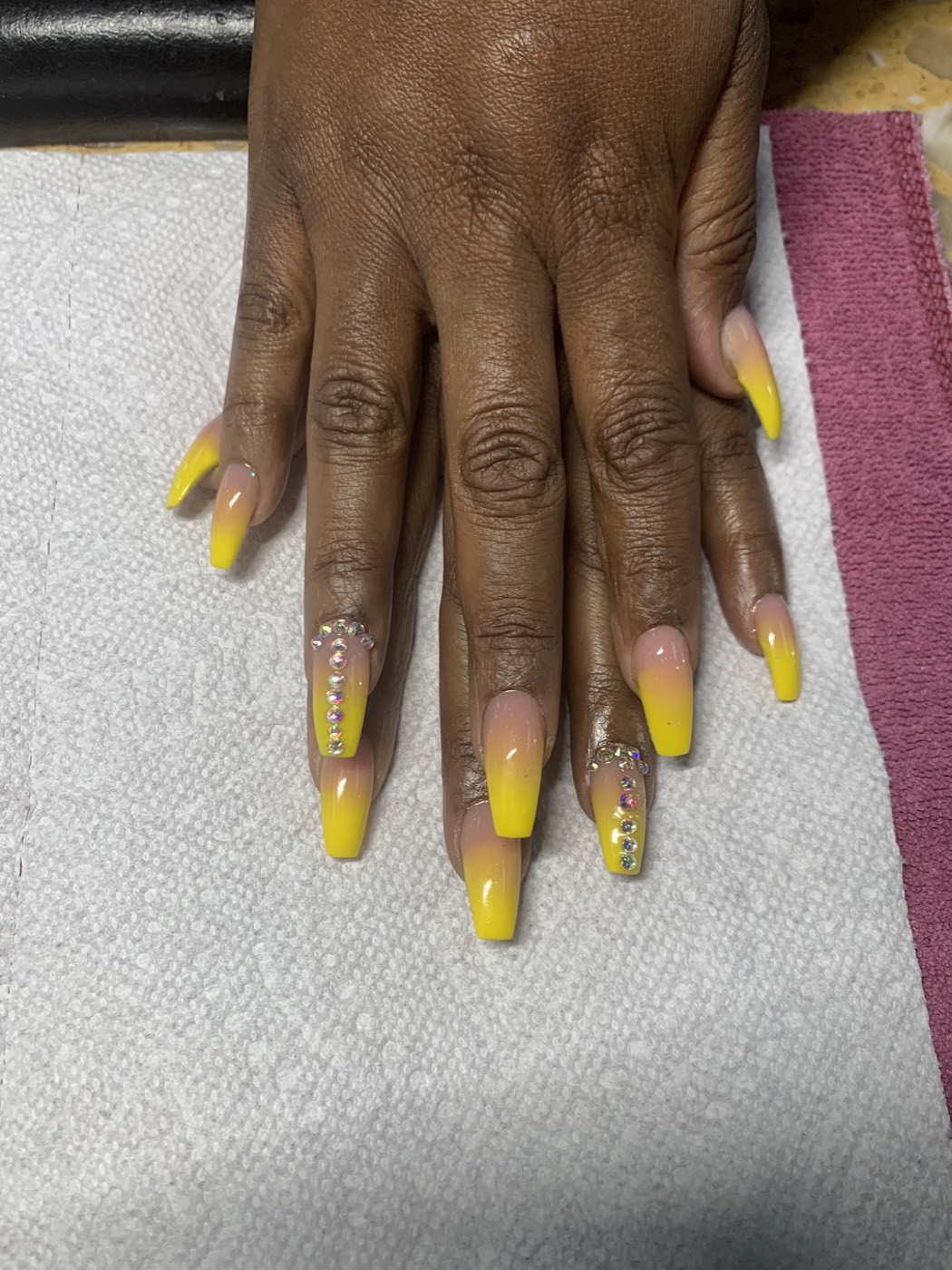 Long coffin nails in a bright yellow ombré with rows of clear rhinestones